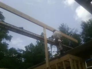 Carpenter setting a ridge beam over a new addition frame — Ice Dam Removal by Roofing Brothers in Lonepine