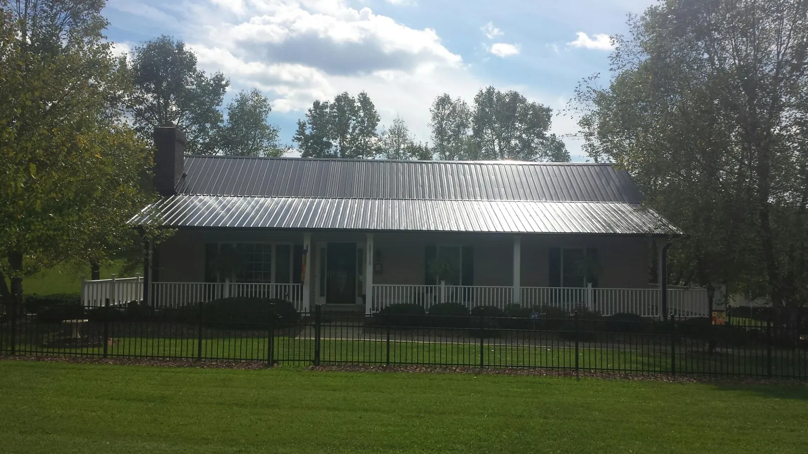 Gray metal roof on a brick ranch with a full width front porch — Gutter Guard Installation work by our crew in Lonepine