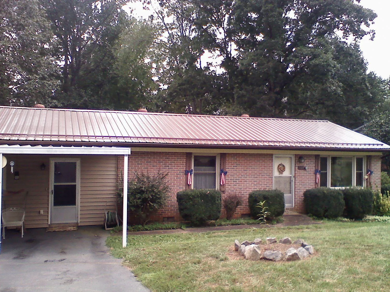 Bronze metal roof and carport on a brick ranch home — Roof Repair work by our crew in Lonepine
