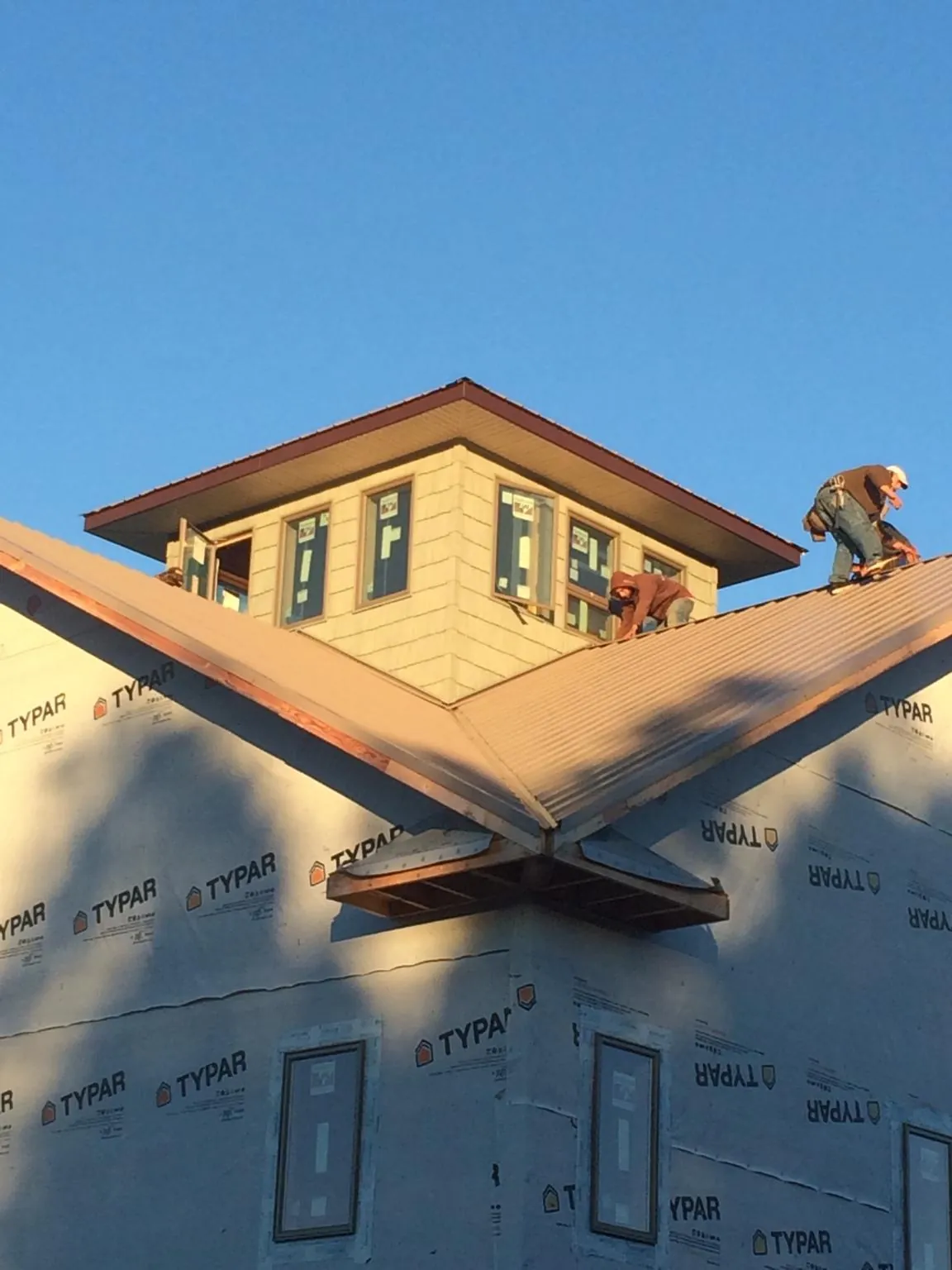Roofers working around a rooftop cupola on a new metal roof at sunset — Roof Waterproofing in Lonepine by Roofing Brothers